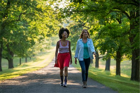 Two women walking down a path lined with trees. Stock Photo - Premium Royalty-Free, Code: 6118-07203406