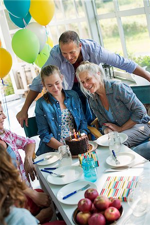 A birthday party in a farmhouse kitchen. A group of adults and children gathered around a chocolate cake. Stock Photo - Premium Royalty-Free, Code: 6118-07203425