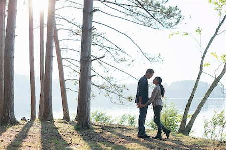 Lakeside. A couple walking in the shade of pine trees in summer. Stock Photo - Premium Royalty-Free, Code: 6118-07203567