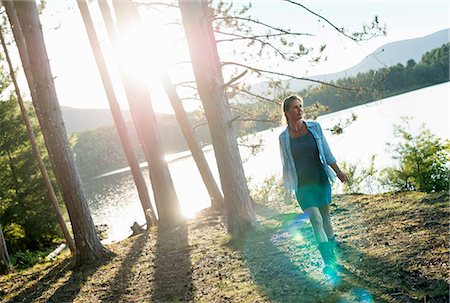 simsearch:6118-07203926,k - A woman standing in the shadows of tall trees on the shores of a lake in summer. Foto de stock - Sin royalties Premium, Código: 6118-07203640