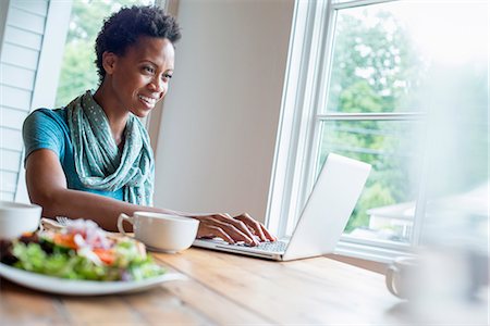 simsearch:6118-07203660,k - A woman sitting in a cafe with a cup of coffee and a meal. Using a laptop. Fotografie stock - Premium Royalty-Free, Codice: 6118-07203645