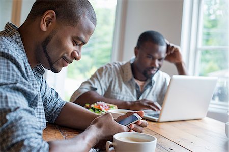 simsearch:6118-07203656,k - Two men sitting in a cafe. Using a laptop and a smart phone. Fotografie stock - Premium Royalty-Free, Codice: 6118-07203648