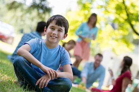 A group of adults and children sitting on the grass under the shade of a tree. A family party. Stock Photo - Premium Royalty-Free, Code: 6118-07203608