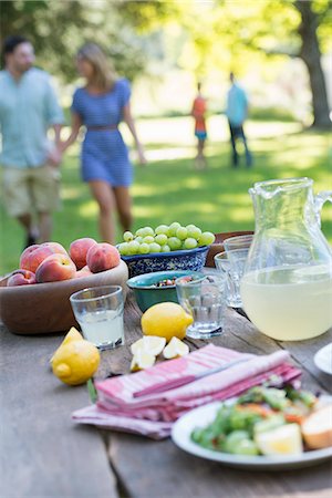 picnic table - A summer buffet of fruits and vegetables, laid out on a table. People in the background. Stock Photo - Premium Royalty-Free, Code: 6118-07203624