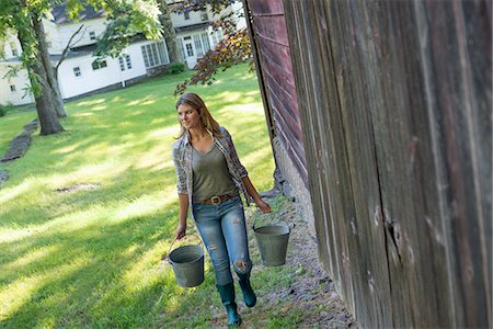 simsearch:6118-07439819,k - A woman carrying a bucket for animal feed in each hand, outside a barn. Stock Photo - Premium Royalty-Free, Code: 6118-07203633