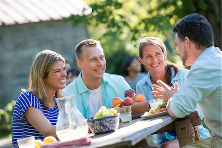 A family, adults and children seated around a table, enjoying a meal together. Stock Photo - Premium Royalty-Free, Code: 6118-07203632