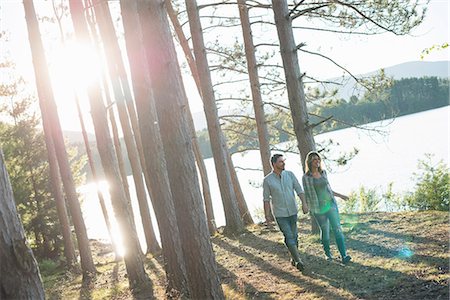 fraternité - A couple walking in woodland on the shores of a lake. Photographie de stock - Premium Libres de Droits, Code: 6118-07203636