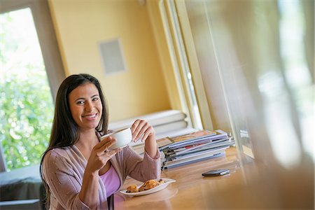 simsearch:6118-07203830,k - A woman having a cup of coffee. A smart phone lying on the table. Stock Photo - Premium Royalty-Free, Code: 6118-07203783