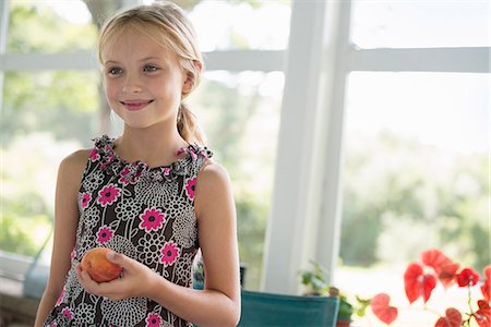simsearch:6118-07203741,k - A young girl in a floral dress holding a peach fruit. Stock Photo - Premium Royalty-Free, Code: 6118-07203729