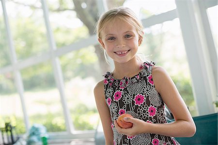 simsearch:6118-07203830,k - A young girl in a floral dress holding a peach fruit. Stock Photo - Premium Royalty-Free, Code: 6118-07203730