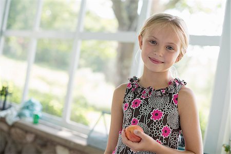 simsearch:6118-07203741,k - A young girl in a floral dress holding a peach fruit. Stock Photo - Premium Royalty-Free, Code: 6118-07203731