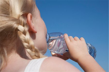 A young child with blonde hair in pigtails, drinking water from a clear bottle. Foto de stock - Sin royalties Premium, Código: 6118-07203840