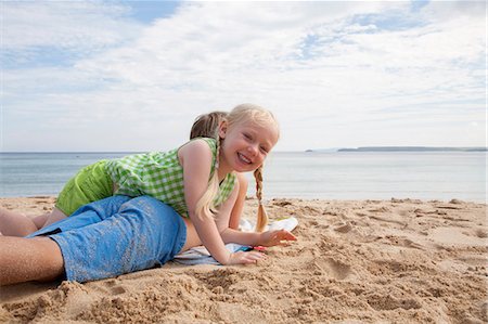 simsearch:6118-07203845,k - A boy lying on his front on the sand looking out to sea. His sister lying on top of him. Stock Photo - Premium Royalty-Free, Code: 6118-07203852