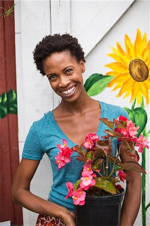 simsearch:6118-07203712,k - Working on an organic farm. A woman holding a large flowering plant, a begonia with pink petals. Foto de stock - Royalty Free Premium, Número: 6118-07203888