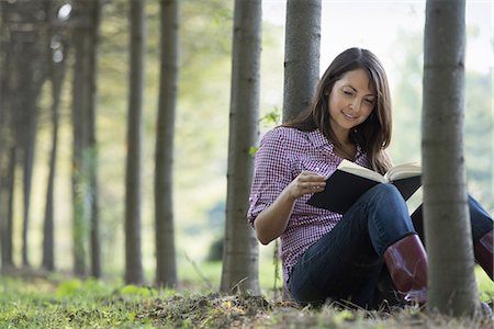 simsearch:6118-07235275,k - A woman sitting reading a book under the trees. Photographie de stock - Premium Libres de Droits, Code: 6118-07235125