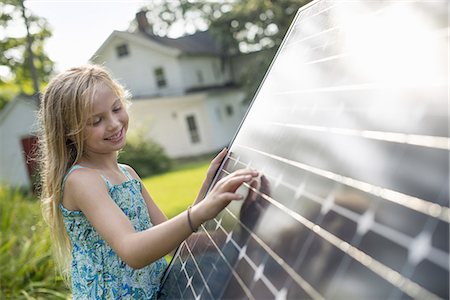 sustainable resource - A young girl beside a large solar panel in a farmhouse garden. Photographie de stock - Premium Libres de Droits, Code: 6118-07235256