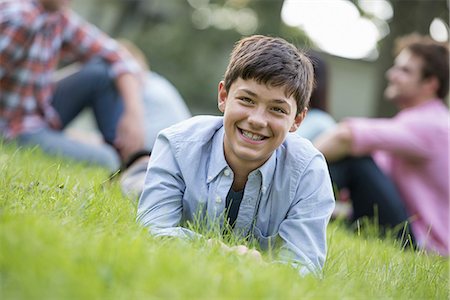 A boy sitting on the grass, at a summer party. Stock Photo - Premium Royalty-Free, Code: 6118-07235261