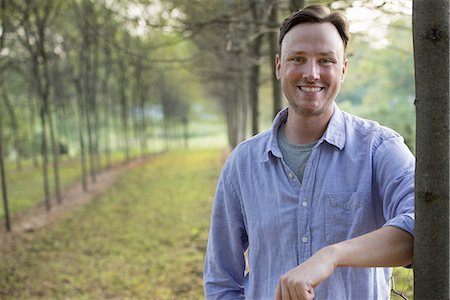 simsearch:6118-07235126,k - A man leaning against a tree, looking at the camera. Foto de stock - Royalty Free Premium, Número: 6118-07235281