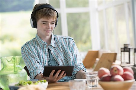 A young boy listening to music and using a digital tablet. Stock Photo - Premium Royalty-Free, Code: 6118-07235229