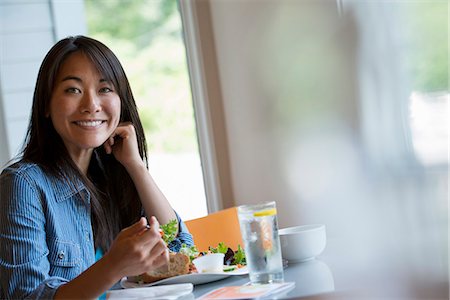 simsearch:6118-07351183,k - A woman seated eating in a cafe. Foto de stock - Royalty Free Premium, Número: 6118-07351156