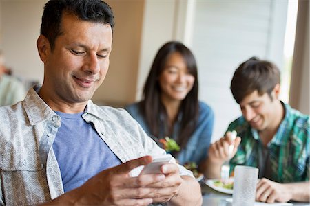 simsearch:6126-09204310,k - Three people seated at a cafe table. Photographie de stock - Premium Libres de Droits, Code: 6118-07351167