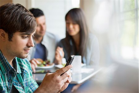 simsearch:6118-07203656,k - Three people seated at a cafe table. Fotografie stock - Premium Royalty-Free, Codice: 6118-07351168