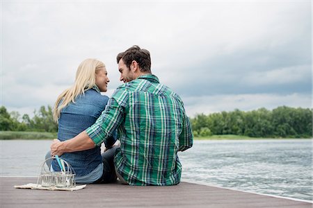 A man and woman seated on a jetty by a lake. Stockbilder - Premium RF Lizenzfrei, Bildnummer: 6118-07351263