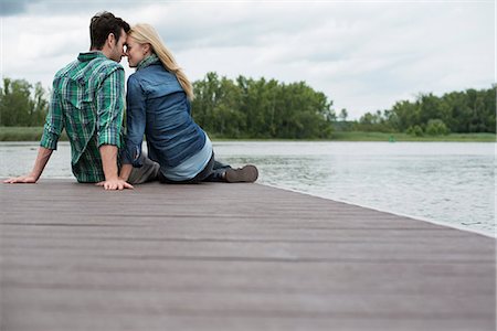 einander ansehen - A man and woman seated on a jetty by a lake. Stockbilder - Premium RF Lizenzfrei, Bildnummer: 6118-07351266
