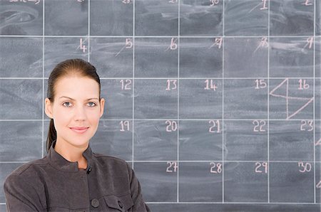 A young woman in front of a blackboard marked out as a calendar. Foto de stock - Sin royalties Premium, Código: 6118-07351298