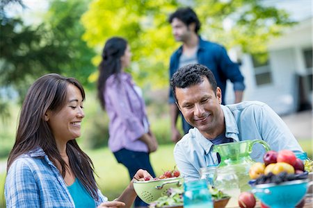 fruits salad in a container - A summer party outdoors. A couple seated at a table. Stock Photo - Premium Royalty-Free, Code: 6118-07351213