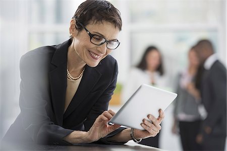 An office interior. A woman in a black jacket using a digital tablet. Foto de stock - Sin royalties Premium, Código: 6118-07351357
