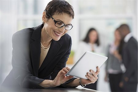 red de contactos - An office interior. A woman in a black jacket using a digital tablet. Foto de stock - Sin royalties Premium, Código: 6118-07351357