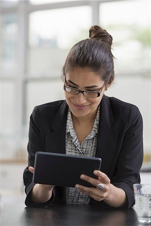 simsearch:614-06896571,k - Young professionals at work. A woman wearing a black jacket, using a black digital tablet. Fotografie stock - Premium Royalty-Free, Codice: 6118-07351364