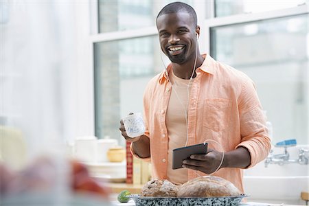 simsearch:6118-07440248,k - An office or apartment interior in New York City. A man in an orange shirt at the breakfast bar, having a cup of tea. Photographie de stock - Premium Libres de Droits, Code: 6118-07351371