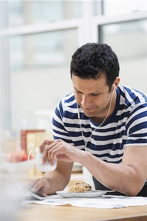 simsearch:6118-07440248,k - An office or apartment interior in New York City. A man in a striped tee shirt leaning on the breakfast bar. Photographie de stock - Premium Libres de Droits, Code: 6118-07351384