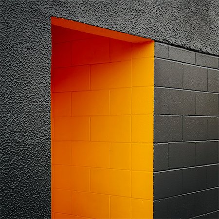 A doorway recess, painted orange in a grey block concrete wall. Stock Photo - Premium Royalty-Free, Code: 6118-07351316