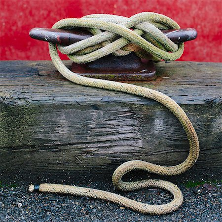 Close up of a wharfside mooring cleat with a fishing boat rope tied around it. Stock Photo - Premium Royalty-Free, Code: 6118-07351323