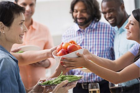 An open plan office in New York City. A working lunch, a salad buffet. A group of men and women of mixed ages and ethnicities meeting together. Stock Photo - Premium Royalty-Free, Code: 6118-07351442