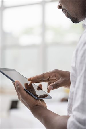 Professionals in the office. A light and airy place of work. A man in a white shirt using a digital tablet. Fotografie stock - Premium Royalty-Free, Codice: 6118-07351459