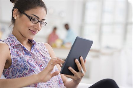 simsearch:6118-07351421,k - Professionals in the office. A light and airy place of work. A young woman seated using a digital tablet. Foto de stock - Sin royalties Premium, Código: 6118-07351470