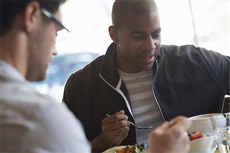 Business people in the city. Keeping in touch on the move. Two men seated at a cafe table, having a meal. Stock Photo - Premium Royalty-Free, Code: 6118-07351474