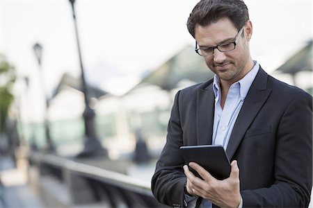 Business people outdoors in the city. Keeping in touch on the move. a man standing holding a digital tablet. Foto de stock - Sin royalties Premium, Código: 6118-07351488