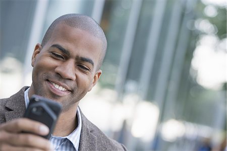 simsearch:6118-07351491,k - Business people in the city. Keeping in touch on the move. A man looking down at his smart phone. Stock Photo - Premium Royalty-Free, Code: 6118-07351492