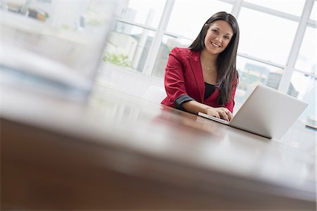 Business people. The office in summer. A young woman sitting comfortably in a quiet airy office environment. Using a laptop. Stock Photo - Premium Royalty-Free, Code: 6118-07351413