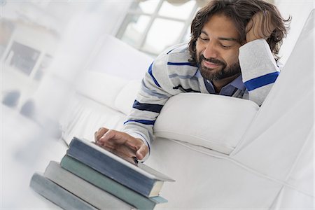 relaxed middle aged business - Business people. The office in summer. A man lying on his stomach on a sofa, in a quiet airy office environment using a smart phone. Stock Photo - Premium Royalty-Free, Code: 6118-07351424