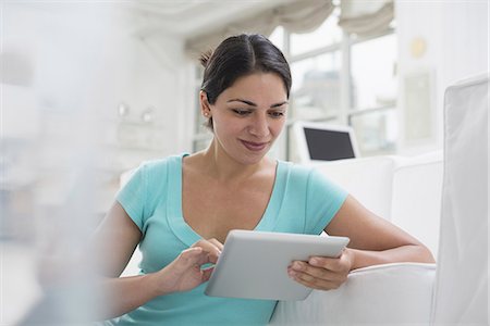 Business people. The office in summer. A young woman sitting comfortably in a quiet airy office environment. Using a digital tablet. Photographie de stock - Premium Libres de Droits, Code: 6118-07351428