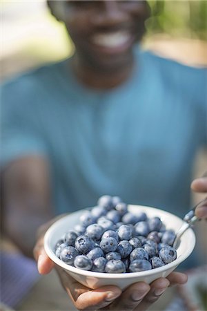 pov - A family picnic meal in the shade of tall trees. Man holding a bowl of fresh blueberries. Stock Photo - Premium Royalty-Free, Code: 6118-07351547