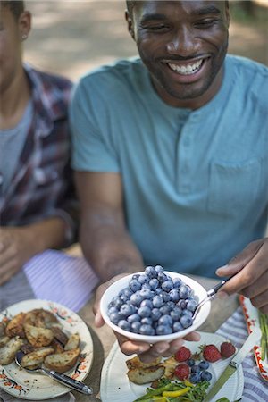 family meal - A family picnic meal in the shade of tall trees. Man holding a bowl of fresh blueberries. Stock Photo - Premium Royalty-Free, Code: 6118-07351546