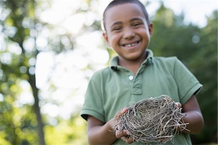A young boy outdoors on a summer day, holding a bird nest. Stock Photo - Premium Royalty-Free, Code: 6118-07351588