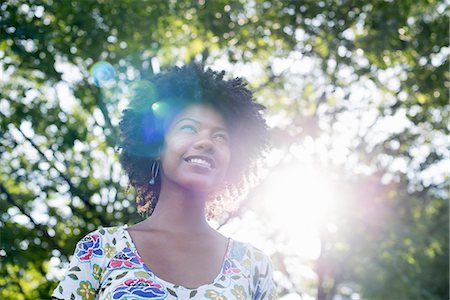 A young woman in a flowered summer dress with her hands behind her head, smiling and looking up. Stockbilder - Premium RF Lizenzfrei, Bildnummer: 6118-07351592